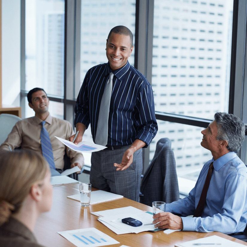 A man presenting ideas to colleagues in a modern office meeting.